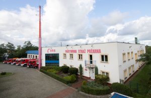 Budynek, w tle wozy strażackie