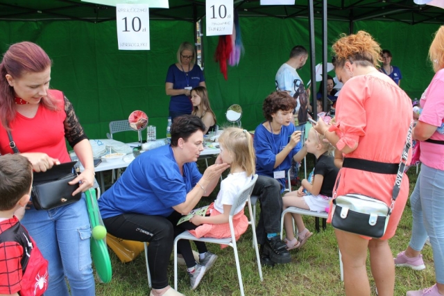 Stoisko z malowaniem twarzy dla dzieci, dziewczynki mają malowane buzie.