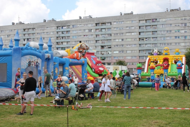 Stoisko z dmuchańcami dla dzieci okupowane przez dzieci i rodziców.