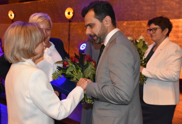 Mężczyzna składa życzenia i wręcza kwiaty z upominkiem kobiecie