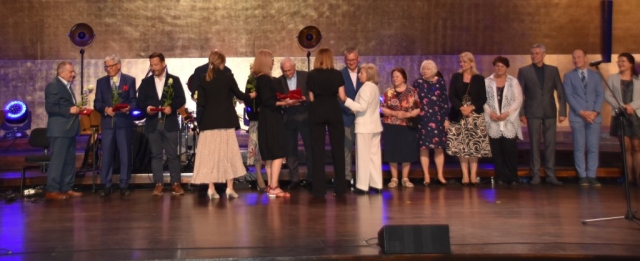 Na scenie stoją osoby wyróżnione za wieloletnią działalność organizacji