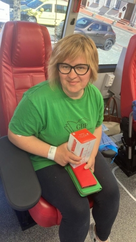 Kobieta siedząca na fotelu, trzymająca w ręku pudełko czekolad, po oddaniu krwi