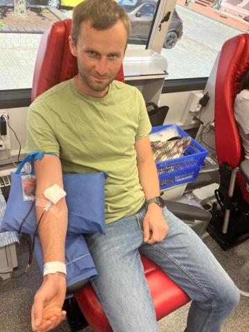 Mężczyzna siedzącay na fotelu, w trakcie oddawania krwi