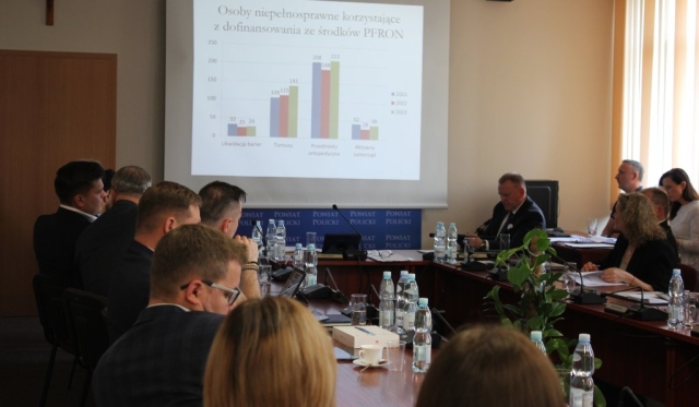 Osoby zebrane na sesji Powiatu w Policach oglądają prezentację odnośnie osób niepełnosprawnych korzystających z dofinansowania ze środków Państwowego Funduszu Rehhabilitacji Osób Niepełnosprawnych