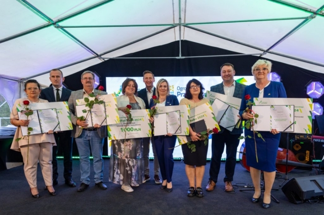 Osoby stojące na scenie, trzymają w rękach dyplomy i róże