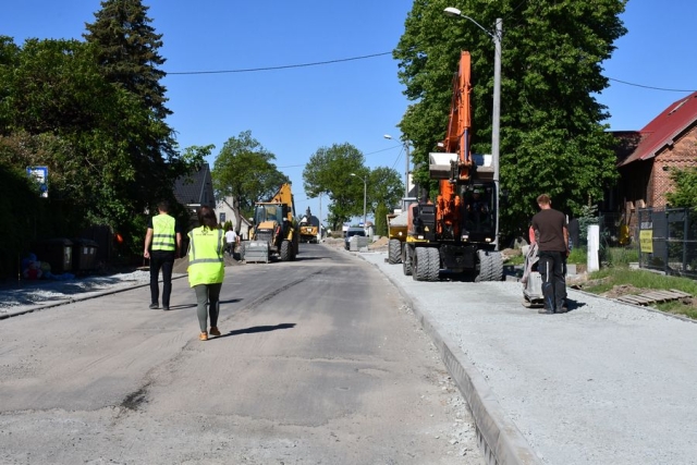 Pracownicy podczas remontu drogi, w tle koparki