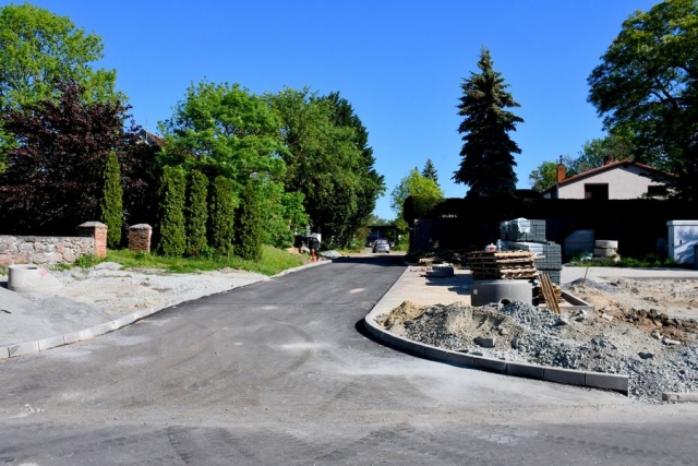 Remont drogi, trwają prace układania krawężników ,w tle zielone drzewa i krzewy