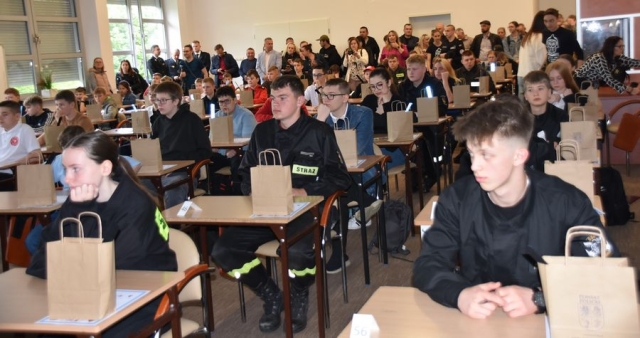 Uczestnicy konkursu pożarniczego siedzą w ławkach