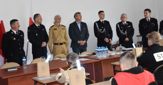Strażacy wraz z Członkiem Zarządu Powiatu Polickiego poczas przemawiania do uczestników konkursu.
