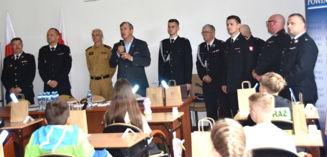 Strażacy wraz z Członkiem Zarządu Powiatu Polickiego poczas przemawiania do uczestników konkursu.