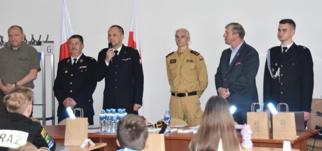 Strażacy wraz z Członkiem Zarządu Powiatu Polickiego poczas przemawiania do uczestników konkursu.