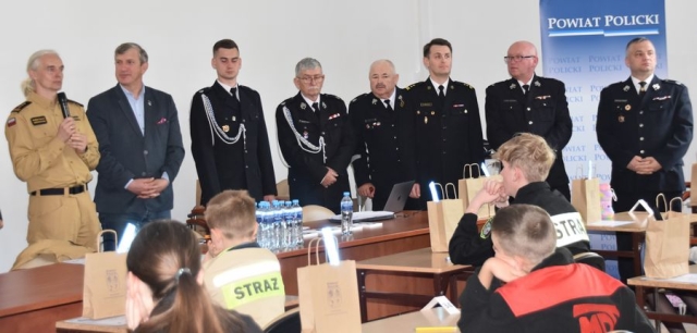 Strażacy wraz z Członkiem Zarządu Powiatu Polickiego poczas przemawiania do uczestników konkursu.