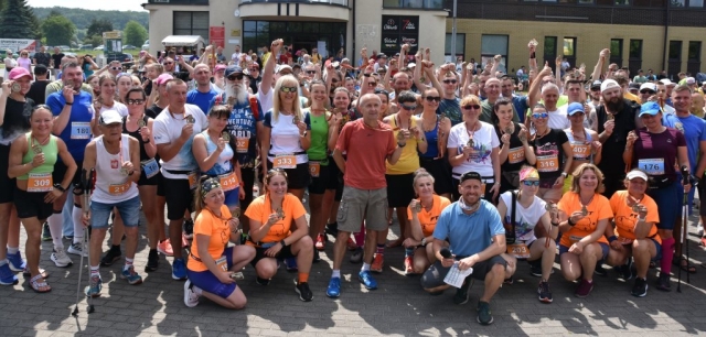 Biegacze pozują do zdjęcia grupowego z medalami za ukończony udział w wydarzeniu.