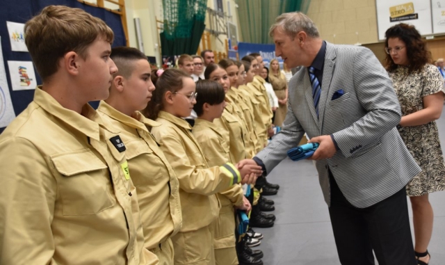 Członek Zarządu Powiatu w Policach podaje rękę oraz upominek składając gratulacje dla uczniów