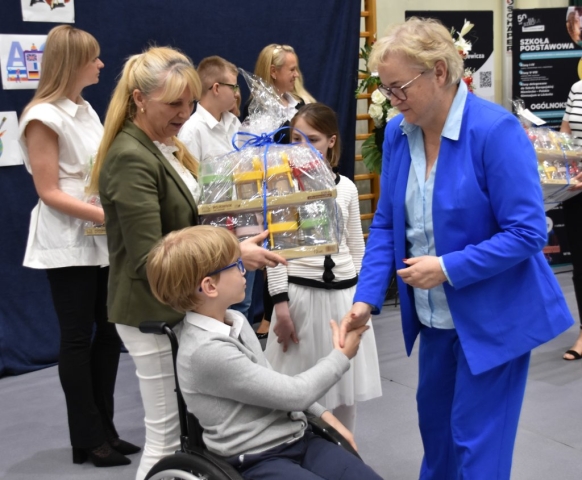 Wiceprzewodnicząca Rady Powiatu w Policach Danuta Chylewska-Kęsy podaje rękę w ramach gratulacji dla nagrodzonego ucznia