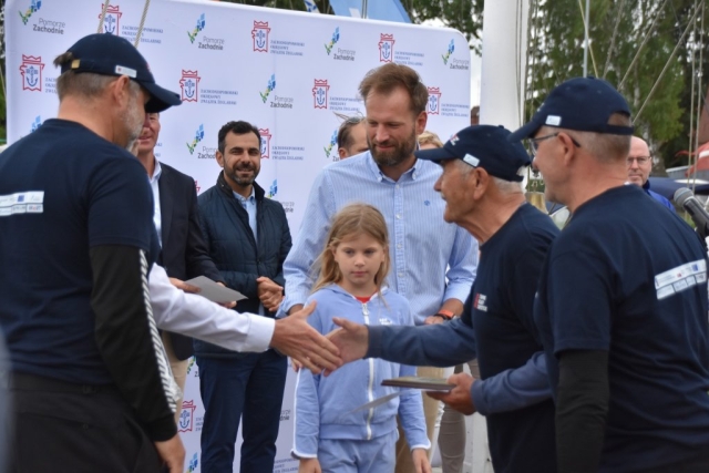 Uczestnicy wraz z organizatorem wydarzenia podają sobie dłonie