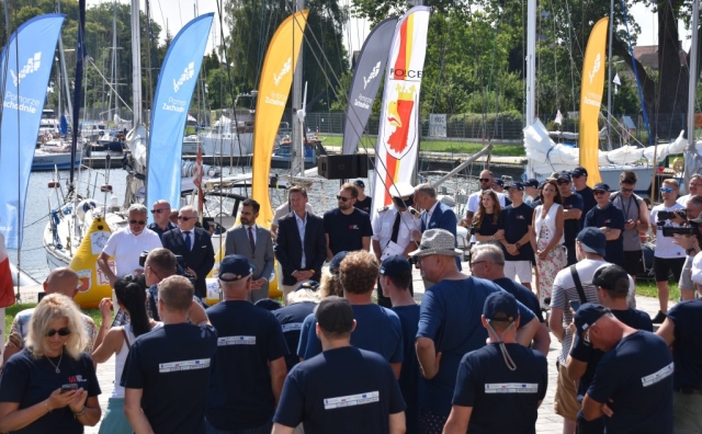 Widok na wodę, zebranych gości oraz uczestników podczas wydarzenia.