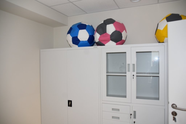 Zdjęcie jasnej szafy, na której znajdują się kolorowe piłki do siedzenia