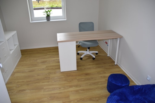 Zdjęcie odremontowanego pokoju, w którym znajdują się jasne meble i pufy do siadania.