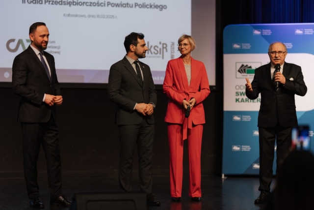 Przewodniczacy Rady Powiatu w Policach przemawia do mikrofonu, jest na scenie z innymi honorowymi gośćmi