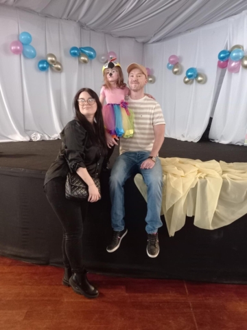 Uśmiechnięta dziewczynka pozuje do zdjęcia z rodzicami