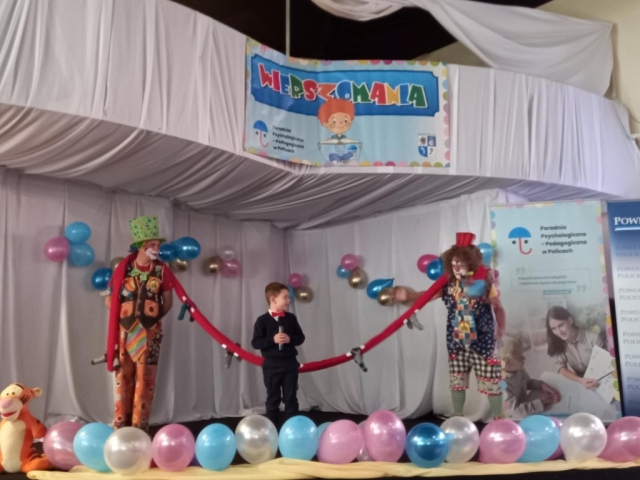 Występ uchłopca w towarzystwie rozbawionych klaunów na scenie