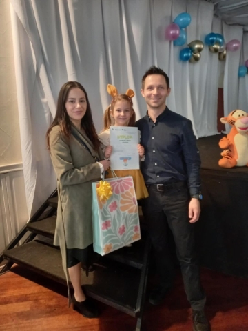 Uśmiechnięta dziewczynka pozuje do zdjęcia z rodzicami